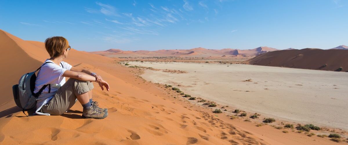 Relaxed tourist sitting on sand dunes and looking at the stunnin